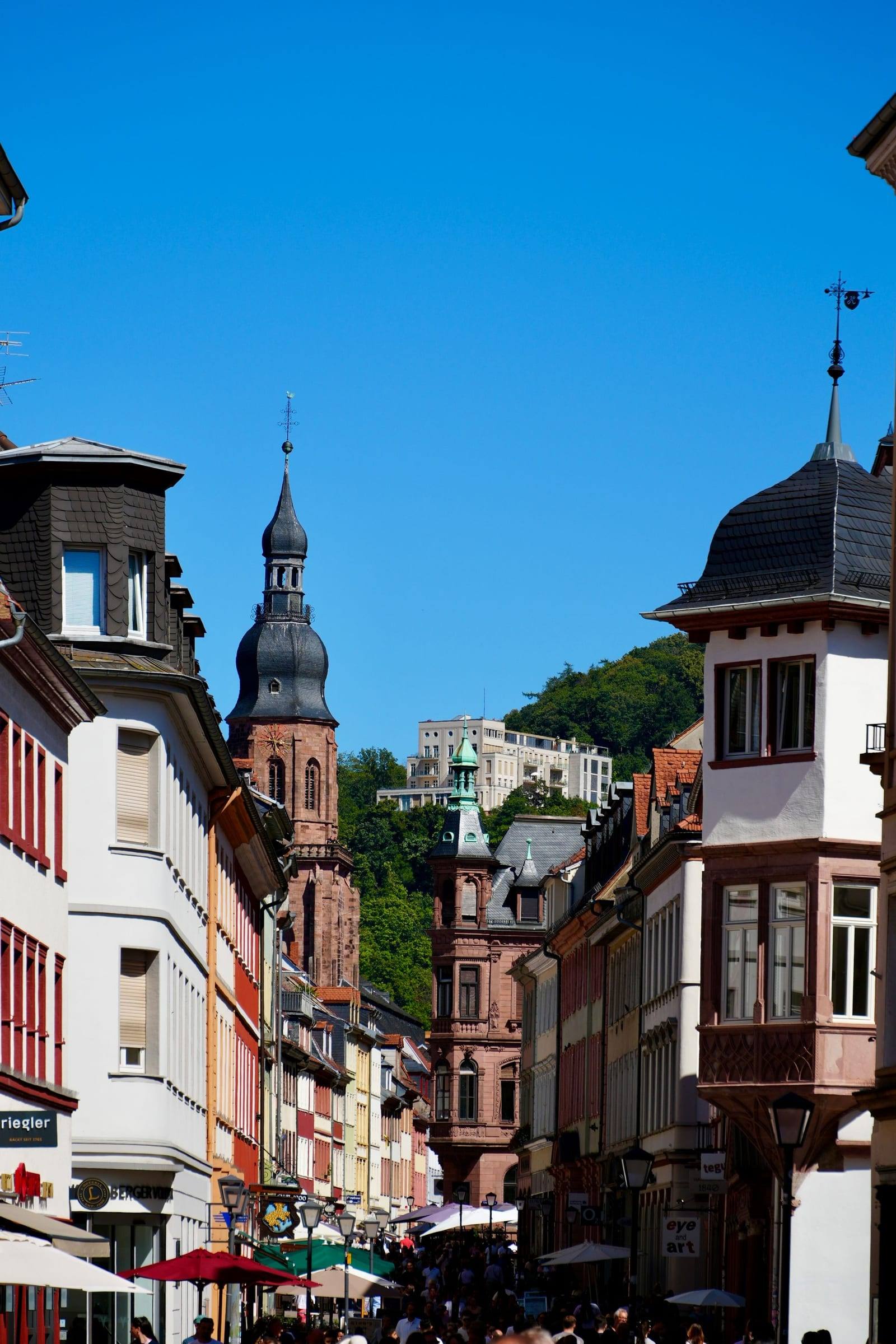 Erker, Türmchen und Kirchturm an der Hauptstraße unter blauem Himmel